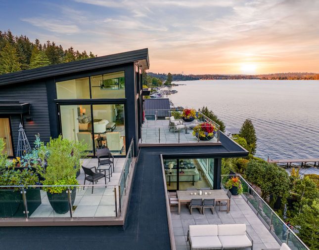 The home’s handsome black exterior contrasts perfectly against the decks’ porcelain pavers. The newly elevated primary suite’s roof slants dramatically toward the sunset.