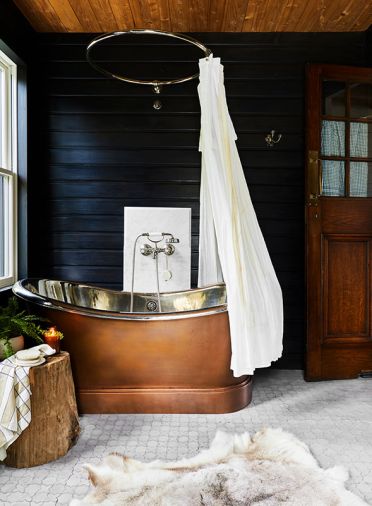 A copper soaking tub with nickel plated interior from Signature Hardware pops against the blackened walls.