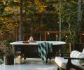 A salvaged clawfoot tub perches upon the wraparound galvanized perforated metal decking, assuring privacy thanks to the well-forested 12-acre plot of land. A Room & Board Breeze chair awaits alongside.