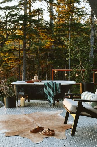 A salvaged clawfoot tub perches upon the wraparound galvanized perforated metal decking, assuring privacy thanks to the well-forested 12-acre plot of land. A Room & Board Breeze chair awaits alongside.