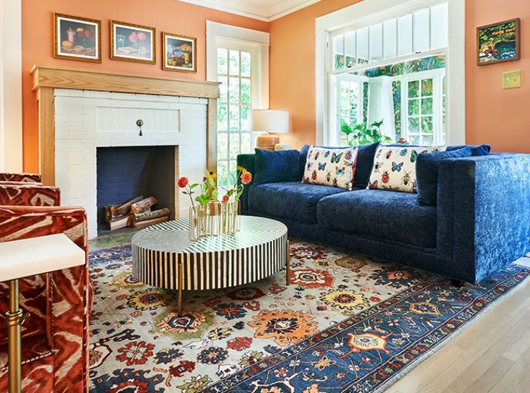 Happy, rich colors enrobe the living room’s walls and furnishings revolving around a multicolored rug.