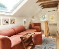 A comfy warm Isla sectional and ottoman glow beneath a new skylight and simple white walls. A Bhatia runner is a focal point leading from staircase to primary suite.