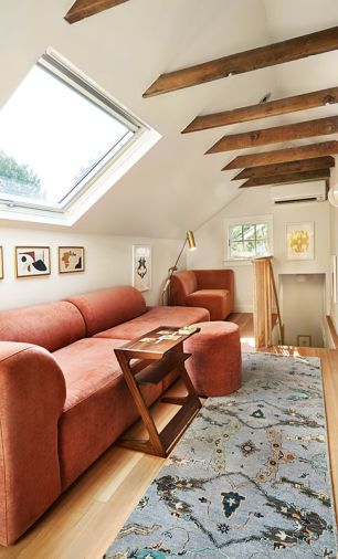 A comfy warm Isla sectional and ottoman glow beneath a new skylight and simple white walls. A Bhatia runner is a focal point leading from staircase to primary suite.