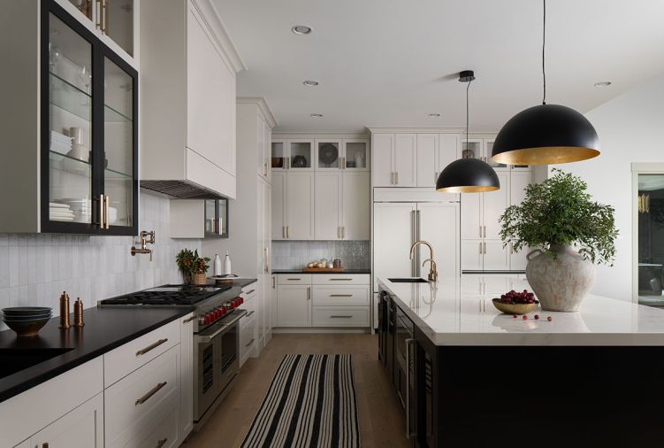Entertaining is made easy with an open floor plan offering clear views of the dining and living room. The two-tone kitchen has cabinetry from LCM Cabinets, painted in “Agreeable Gray” and “Tricorn Black”.