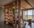 In the sunken living room, a bookshelf room separator from Northwest Custom Cabinets meets a wood ceiling. The Roche Bobois sofa joins a vintage Gaetano Sciolari chandelier, and a Milo Baughman chair and coffee table, both from the Tom Gorz Collection.