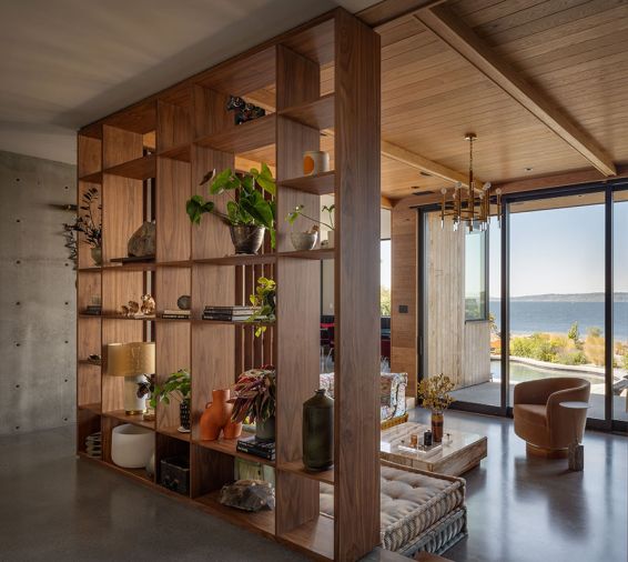 In the sunken living room, a bookshelf room separator from Northwest Custom Cabinets meets a wood ceiling. The Roche Bobois sofa joins a vintage Gaetano Sciolari chandelier, and a Milo Baughman chair and coffee table, both from the Tom Gorz Collection.