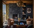 The soapstone hearth pairs with custom plaster on the fireplace by Dawn Bassett. An impressive vintage Brutalist chandelier from Chairish hangs above the handsome Phase Design coffee table.