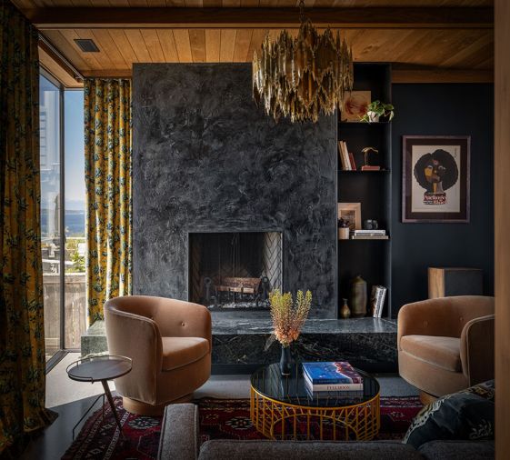 The soapstone hearth pairs with custom plaster on the fireplace by Dawn Bassett. An impressive vintage Brutalist chandelier from Chairish hangs above the handsome Phase Design coffee table.