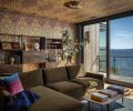 The media room is wrapped in a moody Timorous Beasties wallcovering, and includes vintage shelving, and an inviting Room & Board sofa to take in the view.