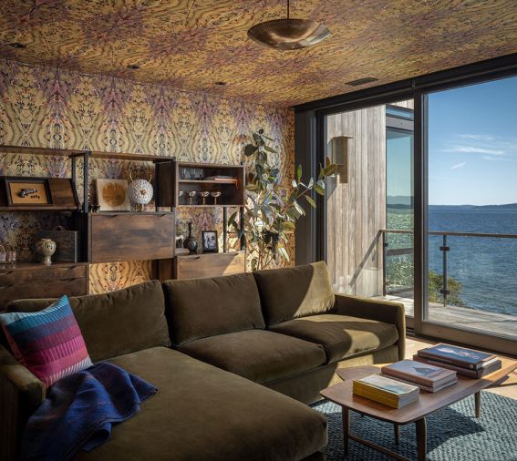 The media room is wrapped in a moody Timorous Beasties wallcovering, and includes vintage shelving, and an inviting Room & Board sofa to take in the view.