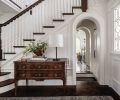 In the foyer, the reconstructed staircase by Oka Woodworks, Inc, has a seven-foot-tall newel post carved in an East Coast facility that could provide a large enough lathe. A lamp from Visual Comfort & Co. sits atop an antique console.