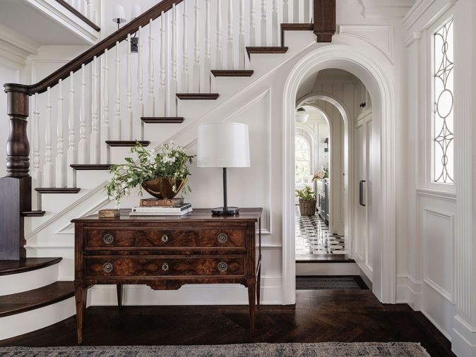 In the foyer, the reconstructed staircase by Oka Woodworks, Inc, has a seven-foot-tall newel post carved in an East Coast facility that could provide a large enough lathe. A lamp from Visual Comfort & Co. sits atop an antique console.