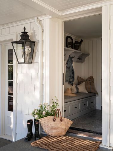 A Colonial lamp illuminates the door to the mudroom, which has Sonoma Tile Makers chevron flooring and a custom bench and coat rack from Northwest Custom Cabinets.