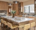 The honey-toned kitchen includes Kelly Wearstler lighting, Vittara Brown quartzite backsplash and counters, and rift white oak cabinetry. Bringing in additional warmth are CB2 barstools, and white oak flooring.