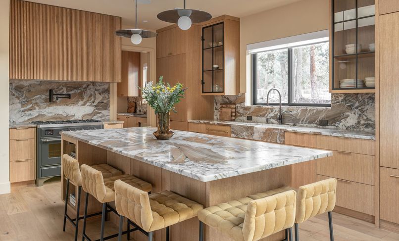 The honey-toned kitchen includes Kelly Wearstler lighting, Vittara Brown quartzite backsplash and counters, and rift white oak cabinetry. Bringing in additional warmth are CB2 barstools, and white oak flooring.