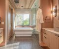 Various natural materials were combined for a welcoming primary bathroom, including fluted lapidary tile from Clé that adds depth behind the freestanding tub and continues into the shower. The wood ceiling syncs with the rift white oak cabinetry and Ann Sacks floor tile.