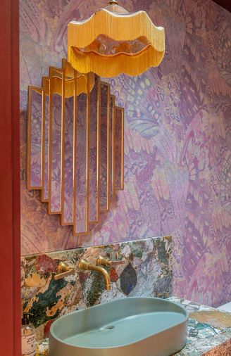 The powder room features the “Aflutter” butterfly wing design, printed on a beautiful textured paper wallcovering by Phillip Jeffries. Added room elements include a 1920's inspired mirror, a complementary slope-sink, and custom pendant light.