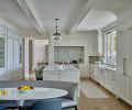 Stunning flow-matched Calacatta Gold marble counters and backsplash shine amidst the reconfigured kitchen, featuring new floor-to-ceiling cabinets (left), crown molding, and ceiling beams.