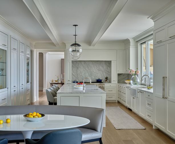 Stunning flow-matched Calacatta Gold marble counters and backsplash shine amidst the reconfigured kitchen, featuring new floor-to-ceiling cabinets (left), crown molding, and ceiling beams.
