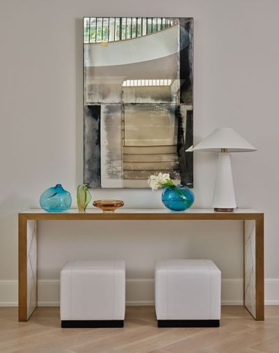 The home’s flooring was replaced with white oak flooring from Eurocraft Hardwood Floors, LLC (now Montello Design). Homeowners’ curated artwork is reflected in a mirror along with stairwell and mezzanine.