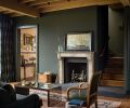 Exposed Douglas fir beams and vintage oak flooring are tempered with rich wall hues. The custom carved fireplace and limestone surround was handcrafted by Lambert Stoneworks.