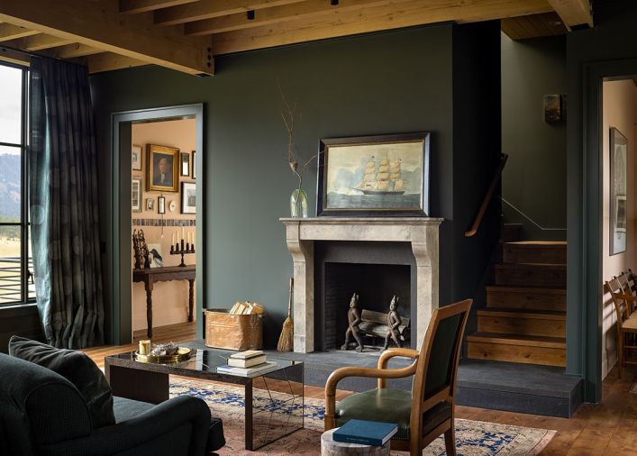 Exposed Douglas fir beams and vintage oak flooring are tempered with rich wall hues. The custom carved fireplace and limestone surround was handcrafted by Lambert Stoneworks.