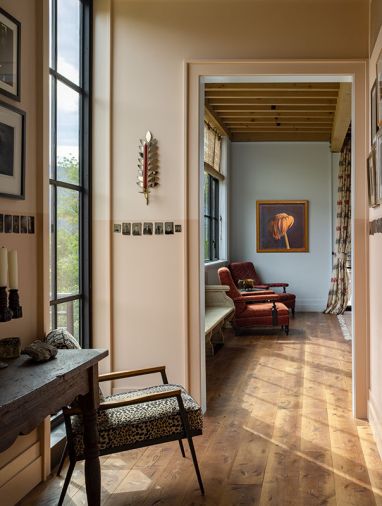 The hallway provides space for the owners’ multifaceted collection of art and antiques. Large windows allow for prairie views and ample natural light.