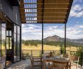 Outdoor patios on both ends of the home feature stile and rail wood panel doors which lead to expansive views and easy access to indoor and outdoor dining. Round pipe railings are reminiscent of a farm gate.