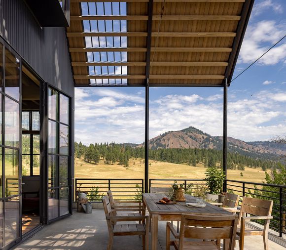 Outdoor patios on both ends of the home feature stile and rail wood panel doors which lead to expansive views and easy access to indoor and outdoor dining. Round pipe railings are reminiscent of a farm gate.