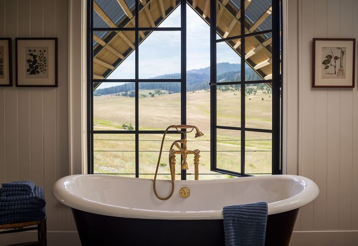 A Kohler Freestanding Cast Iron Tub with Watermark tub filler is strategically placed for the perfect bathing spot with windows that swing wide to summer breezes.
