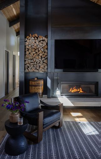 The fireplace has an industrial feel, which sets it apart from the white walls and wood cladding. The metalwork was done by Devotion Industries, the sling chair is from Four Hands.