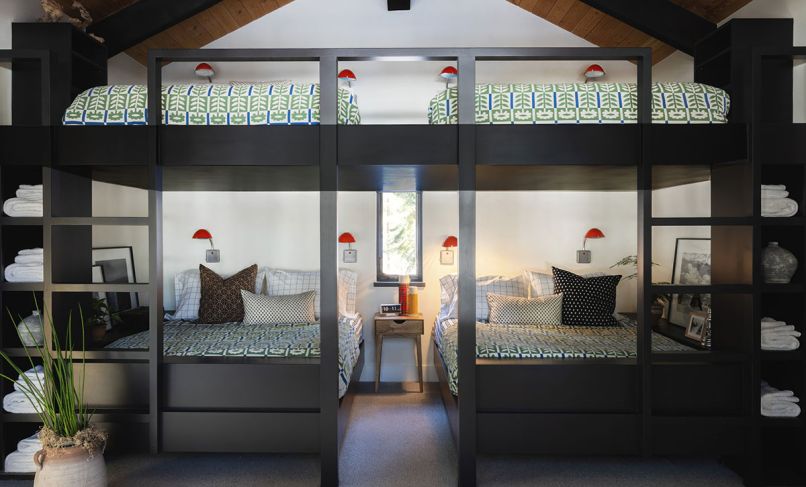 In the bunk room, the custom bunks are designed by Olin Architecture and built by Dyer Construction, with sconces and quilts from Schoolhouse Portland.
