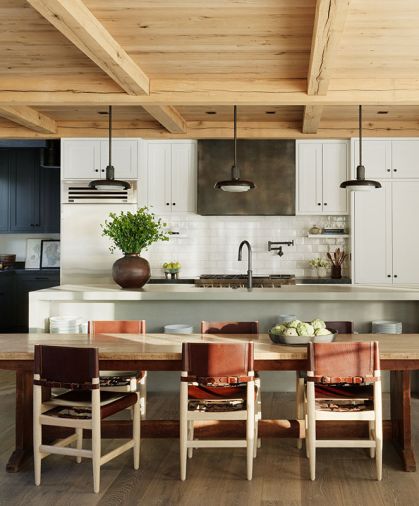 The York College refectory table grounds the reclaimed white oak ceiling. The kitchen is framed by a custom concrete counter and island and Ann Sacks handmade Idris tile by Ait Manos.