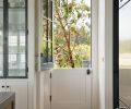 Adding to the charm of the home, a Dutch door by Northstar Woodworks brings the fresh air in. The glass cabinet doors reiterate the mullioned exterior windows.