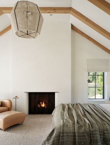 A Cuff Studio pendant adorns the primary suite, which is grounded by a fireplace from Sutter Home & Hearth and nubbly Marc Phillips rug.