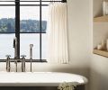 The primary bath features a cozy Penhaglion stainless steel tub overlooking the waters of the peninsula with handy shelves nearby.