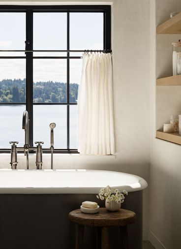 The primary bath features a cozy Penhaglion stainless steel tub overlooking the waters of the peninsula with handy shelves nearby.