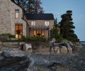 Seen at night against the peninsula’s calm waters, 100-year-old trees are an elegant backdrop, along with the rocky landscape. The home’s limestone glows in the moonlight, while Western red cedar siding and standing seam roof frames the structure.