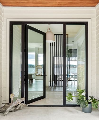 Guests are greeted by a Fleetwood door and windows from Cherry Creek Windows & Doors as they enter the beach home across a porcelain tile entryway.