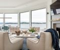 To the left of the entry features the living room’s U-shaped sectional and to the right, four Ethnicraft linen lounge chairs and whitewashed Douglas Fir coffee table. Windows open for the sea breeze and shades of blue accessories echo the water hues beyond.