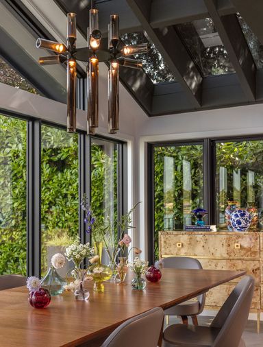 Lighting from Roll & Hill hangs above the rich walnut Cross Extension Table from Design Within Reach. A Burlwood Three-Drawer Chest from Burke Décor holds pretty family finds.
