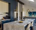 In the kitchen, the two-tone cabinetry is from Baywood Cabinet, Inc., with uppers in “Wool Skein”, and lowers in “Gale Force”, both by Sherwin Williams. Progranite Surfaces llc provided the stone fabrication for the Calacatta Gold Extra Select counters and backsplash.