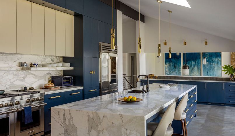 In the kitchen, the two-tone cabinetry is from Baywood Cabinet, Inc., with uppers in “Wool Skein”, and lowers in “Gale Force”, both by Sherwin Williams. Progranite Surfaces llc provided the stone fabrication for the Calacatta Gold Extra Select counters and backsplash.