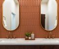 The full-height tile wall highlights the double vanity, featuring Kohler plumbing fixtures and lighting, and cabinetry from Canyon Creek Cabinets.