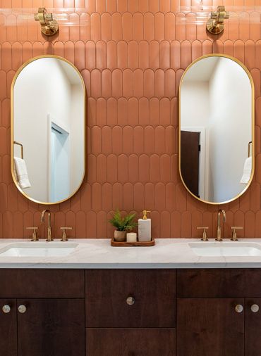 The full-height tile wall highlights the double vanity, featuring Kohler plumbing fixtures and lighting, and cabinetry from Canyon Creek Cabinets.