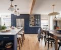 The far wall provides an array of storage, from wall hooks to pantry cabinets surrounding the refrigerator, to a serving alcove with open shelves and dishware displayed behind glass doors.