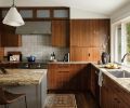 A large window over the Kohler sink with a Delta faucet visually connects the kitchen to the backyard entertaining zone. Pendant lighting provides island illumination.