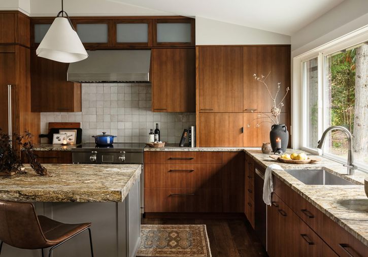 A large window over the Kohler sink with a Delta faucet visually connects the kitchen to the backyard entertaining zone. Pendant lighting provides island illumination.