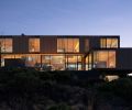 A burnt snag tree with fresh wood interiors inspired the home’s dark exterior and light interiors. Narrow framed aluminum Styline windows tuck into framing and roof.