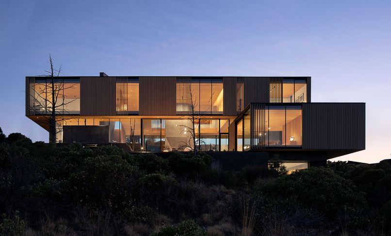 A burnt snag tree with fresh wood interiors inspired the home’s dark exterior and light interiors. Narrow framed aluminum Styline windows tuck into framing and roof.